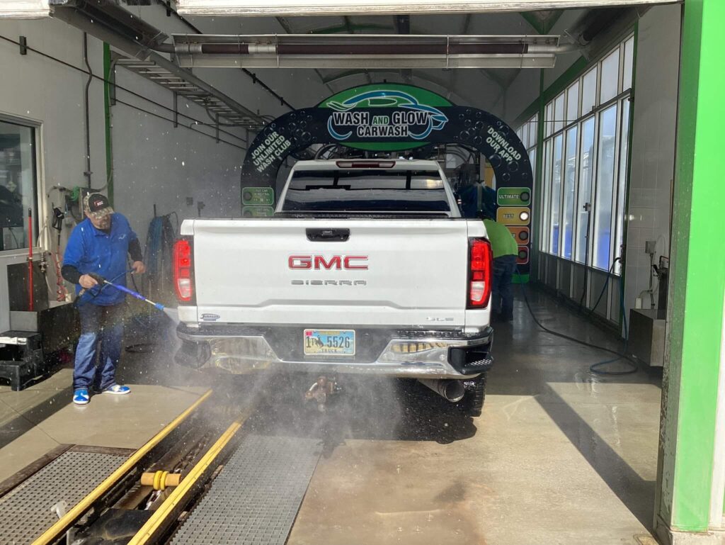 A Wash and Glow attendant rinsing the back of a truck